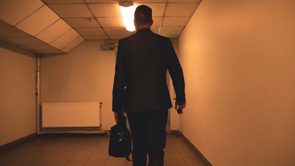 Young handsome guy businessman in a suit, (man) climbs the stairs with a black bag in his hands. Concept: business, suit, guy, man, bag, businessman.