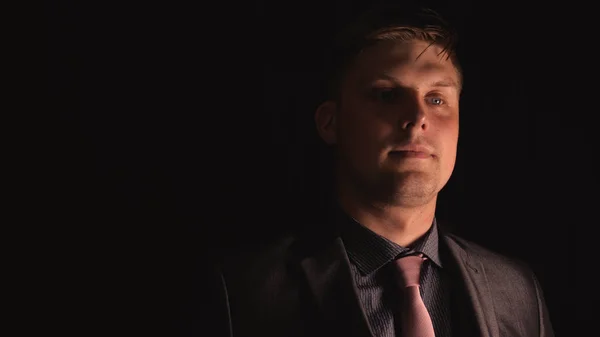 A young handsome guy (man) in a suit looks up in front of a black background. Concept: Man, Young, Think, Look, Suit.