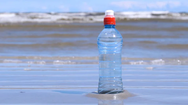 Plastic bottle on the background of the sea. Concept: Sea, Water, Plastic, Bottle, Harm to the Environment, Ecology, Hand.