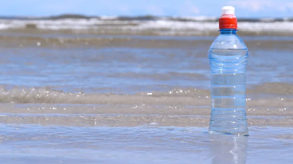 Plastic bottle on the background of the sea. Concept: Sea, Water, Plastic, Bottle, Harm to the Environment, Ecology, Hand.