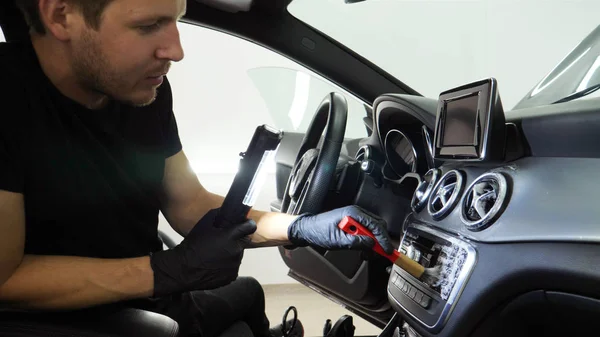 Yakışıklı genç adam, (adam) arabada profesyonel kuru temizleme salonu yapıyor. Konsept: Oto Oto Servisi, Oto Yıkama, Kuru Temizleme Makineleri.