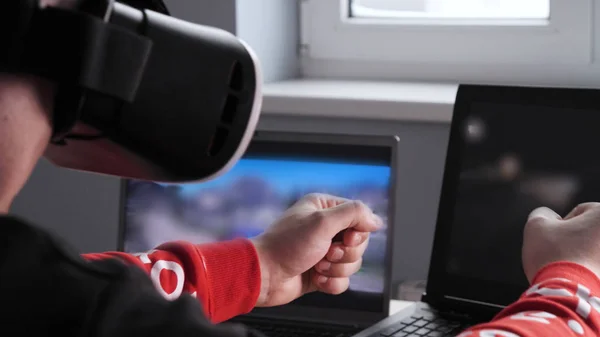 Young guy (male) player in virtual glasses plays (relaxes) against him 2 game monitors, he moves his hands seeing the movement with glasses. Concept of: Lifestyle, Underworld, 3d, Virtual reality