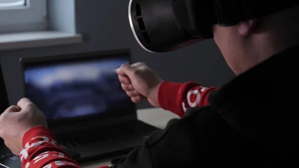 Young guy (male) player in virtual glasses plays (relaxes) against him 2 game monitors, he moves his hands seeing the movement with glasses. Concept of: Lifestyle, Underworld, 3d, Virtual reality