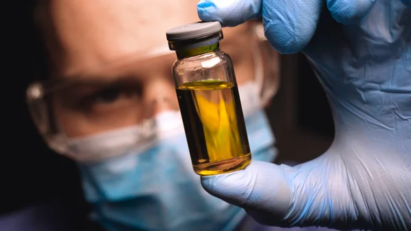 Bir erkek laboratuvar teknisyeni (profesyonel), laboratuvar gözlük bir bilim işçisi, bir test tüpü bakar ve çok dikkatli kan damlar, Erkek doktor gözlük gözlük ile eldiven giyen iş üniforması in vitro analizi inceler. Kavramı: Proffessional d