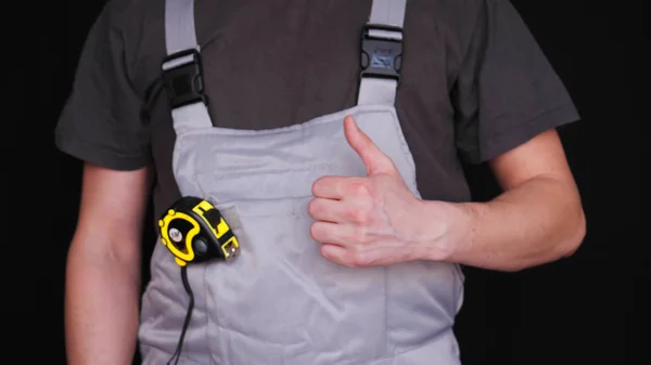 マスター ビルダーや修理工は 特別なスーツ メトリックの黄色のテープメジャー 黒の背景で 彼の手にキャリパーを保持します — ストック写真
