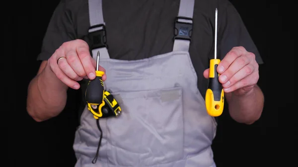 建造者或修理工手里拿着一个卡钳 穿着一件特别的西装 一个黄色的测量指标的磁带 一个黑色的背景 — 图库照片