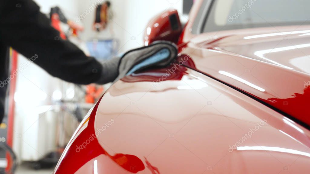 Closely shown as a professional worker polishes the transport (car) body using a polishing tool (machine). Concept from: Auto service, Car Painting, Machine washing.