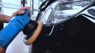 Özel takım elbiseli bir adam bir gri araba vücut, arabalar, bir atölye parlatma için bir araç parlatır.