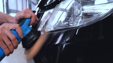 Özel takım elbiseli bir adam bir gri araba vücut, arabalar, bir atölye parlatma için bir araç parlatır.