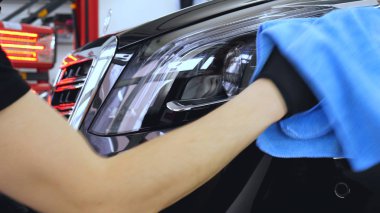 Özel takım elbiseli bir adam bir gri araba vücut, arabalar, bir atölye parlatma için bir araç parlatır.