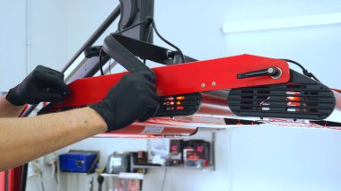 Genç bir profesyonel işçi kırmızı seramik lambalar kurar, bir araba atölyesi, araba yıkama.