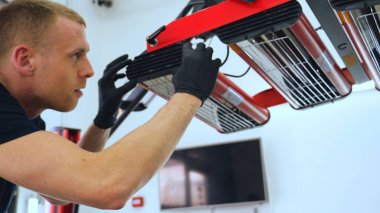 Genç bir profesyonel işçi kırmızı seramik lambalar kurar, bir araba atölyesi, araba yıkama.