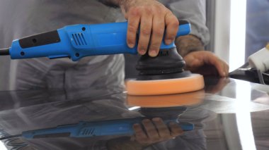 Özel takım elbiseli bir adam bir gri araba vücut, arabalar, bir atölye parlatma için bir araç parlatır.