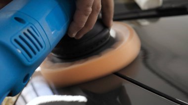 Özel takım elbiseli bir adam bir gri araba vücut, arabalar, bir atölye parlatma için bir araç parlatır.