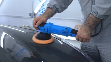 Özel takım elbiseli bir adam bir gri araba vücut, arabalar, bir atölye parlatma için bir araç parlatır.