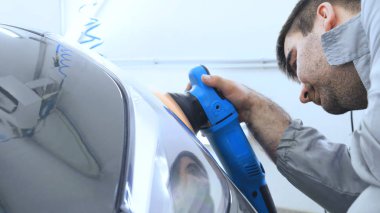 Özel takım elbiseli bir adam bir gri araba vücut, arabalar, bir atölye parlatma için bir araç parlatır.