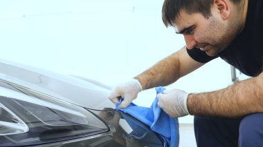 Özel takım elbiseli bir adam bir gri araba vücut, arabalar, bir atölye parlatma için bir araç parlatır.