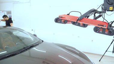 Özel takım elbiseli bir adam bir gri araba vücut, arabalar, bir atölye parlatma için bir araç parlatır.