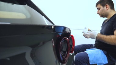 Özel takım elbiseli bir adam bir gri araba vücut, arabalar, bir atölye parlatma için bir araç parlatır.