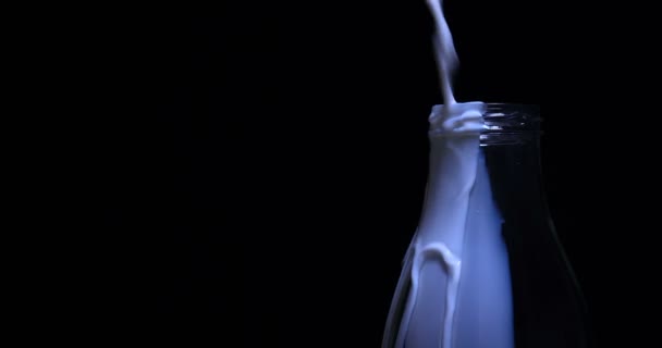 慢慢地把牛奶倒进瓶子里 牛奶放在袋子上的玻璃瓶里 黑色背景 — 图库视频影像