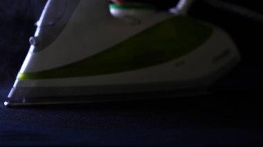 Demir, siyah bir arka planda çok yakındır. Ütü bezi (gömlek) siyahtır; Buhar bir sürü demir çıkıyor. Kavramı: Buhar, Close, siyah.