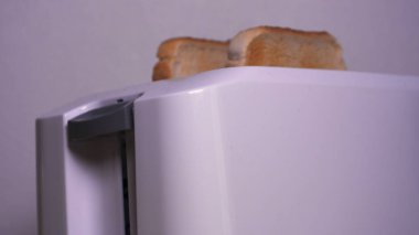 Mutfakta, bir erkek (kız) buzdolabından yiyecek çıkarır ve tost makinesinin yanına kahvaltı hazırlar, hazır ekmek kızartma makineleri çıkarılır. Ev yapımı yemek, rahatlık, kahvaltı, ağır çekim kavramı.