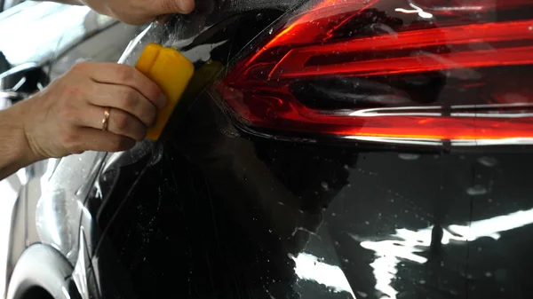 Close up to PPF installation process on a front (rear) headlight and bamper. PPF is a Paint Protection Film which protect paint from scratches and stone chips. Concept of: Film, Car, Service, Slow Mo