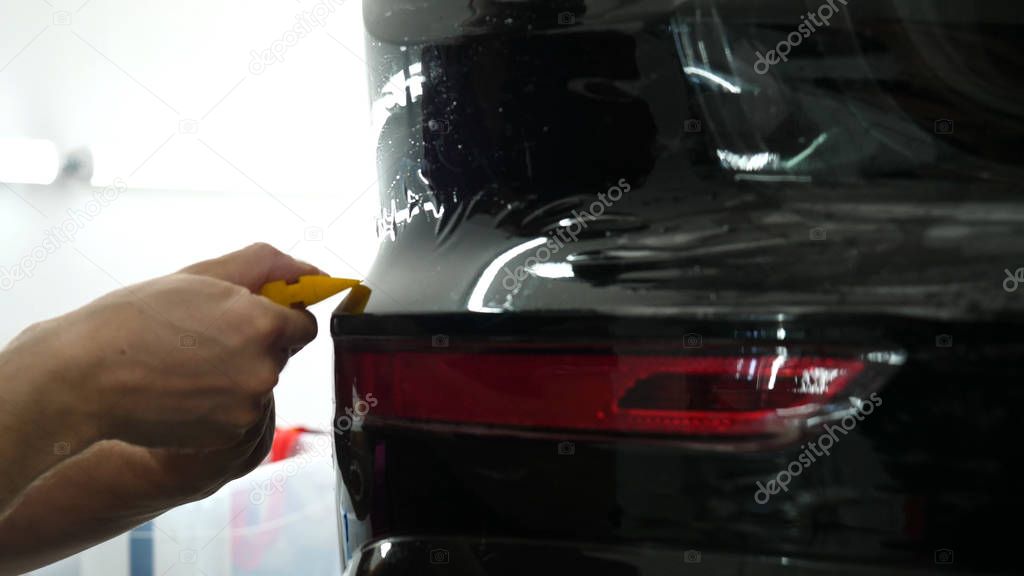 Close up to PPF installation process on a front (rear) headlight and bamper. PPF is a Paint Protection Film which protect paint from scratches and stone chips. Concept of: Film, Car, Service, Slow Mo