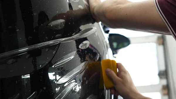 Close up to PPF installation process on a front (rear) headlight and bamper. PPF is a Paint Protection Film which protect paint from scratches and stone chips. Concept of: Film, Car, Service, Slow Mo