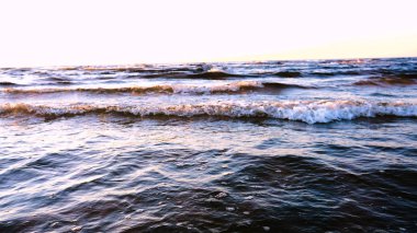 Günbatımının arka planında genç bir kadın deniz kıyısında güneş egzersizlerini koşarak, gerinerek ve düşerek yapar, denizdeki kız yoga yapar. Yavaş çekim, Günbatımı 'nın Portresi.