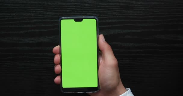 ラトビア 2019 Editorial Mockup Green Screenスマートフォン 閉めろ 携帯電話を保持する男の手のクロマキー画像 のタッチスクリーンでテレビの背景に — ストック動画