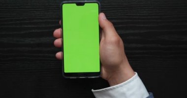 Riga, Letonya - 06 / 06 / 2019 EDITORIAL: Mockup Green Screen Smartphone. Yakın çekim. Erkek Elleri Tutan Cep Telefonu 'nun Chroma Key resmi. Evde televizyonun arkaplanına karşı (çubukta) dokunmatik ekran.