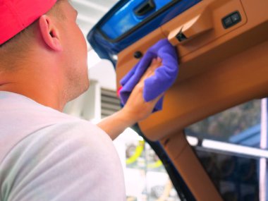 Arabadaki adam bir bez ve basınçlı hava tabancası kullanarak arabanın her yerinden kurur. Konsept: Yeni araba, Kurutma, Tarzı, Lüks sınıf.