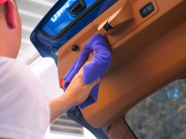 Arabadaki adam bir bez ve basınçlı hava tabancası kullanarak arabanın her yerinden kurur. Konsept: Yeni araba, Kurutma, Tarzı, Lüks sınıf.