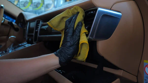 A woman at a car wash does a full dry-cleaning of all parts of a car using special chemistry, cloths, sponges and brushes. Concept of: Full car cleaning, Dry cleaning, Professional service. Car, Work.