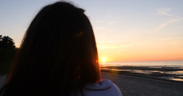 海辺で太陽が沈む夕日を背景に若い女性がランニング ストレッチ 海の少女はヨガをします 肖像画 スローモーション — ストック動画