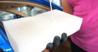 Araba yıkamacıdaki bir kadın özel kimya, giysi, sünger ve fırça kullanarak arabanın tüm parçalarını kuru temizlemeye verir. Tam araba temizliği, kuru temizleme, profesyonel hizmet. Araba, iş.