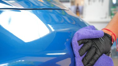 Araba yıkamacıdaki bir kadın özel kimya, giysi, sünger ve fırça kullanarak arabanın tüm parçalarını kuru temizlemeye verir. Tam araba temizliği, kuru temizleme, profesyonel hizmet. Araba, iş.