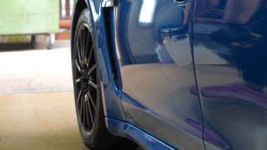 Araba yıkamacıdaki bir kadın özel kimya, giysi, sünger ve fırça kullanarak arabanın tüm parçalarını kuru temizlemeye verir. Tam araba temizliği, kuru temizleme, profesyonel hizmet. Araba, iş.