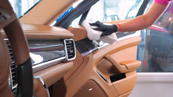 Araba yıkamacıdaki bir kadın özel kimya, giysi, sünger ve fırça kullanarak arabanın tüm parçalarını kuru temizlemeye verir. Tam araba temizliği, kuru temizleme, profesyonel hizmet. Araba, iş.