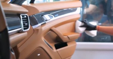 Araba yıkamacıdaki bir kadın özel kimya, giysi, sünger ve fırça kullanarak arabanın tüm parçalarını kuru temizlemeye verir. Tam araba temizliği, kuru temizleme, profesyonel hizmet. Araba, iş.