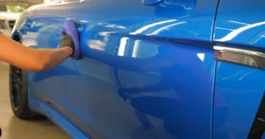 Araba yıkamacıdaki bir kadın özel kimya, giysi, sünger ve fırça kullanarak arabanın tüm parçalarını kuru temizlemeye verir. Tam araba temizliği, kuru temizleme, profesyonel hizmet. Araba, iş.