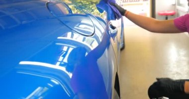 Araba yıkamacıdaki bir kadın özel kimya, giysi, sünger ve fırça kullanarak arabanın tüm parçalarını kuru temizlemeye verir. Tam araba temizliği, kuru temizleme, profesyonel hizmet. Araba, iş.