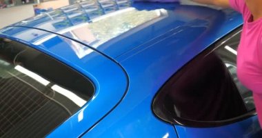 Araba yıkamacıdaki bir kadın özel kimya, giysi, sünger ve fırça kullanarak arabanın tüm parçalarını kuru temizlemeye verir. Tam araba temizliği, kuru temizleme, profesyonel hizmet. Araba, iş.