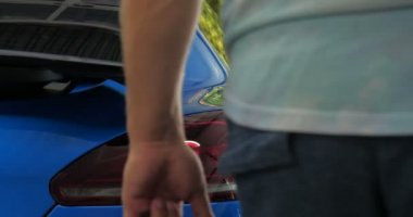 Garajda (Servis) bir adam çantasını salona koyar (bagajda), araba alarmını kontrol eder ve kapatır. Bir adam yeni bir arabanın bagajını ve kapısını açıyor. Yavaş çekim, araba dükkanı, adam.
