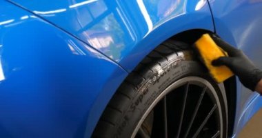 Araba yıkamacıdaki bir kadın özel kimya, giysi, sünger ve fırça kullanarak arabanın tüm parçalarını kuru temizlemeye verir. Tam araba temizliği, kuru temizleme, profesyonel hizmet. Araba, iş.