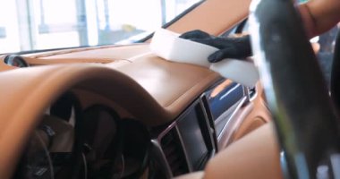 Araba yıkamacıdaki bir kadın özel kimya, giysi, sünger ve fırça kullanarak arabanın tüm parçalarını kuru temizlemeye verir. Tam araba temizliği, kuru temizleme, profesyonel hizmet. Araba, iş.