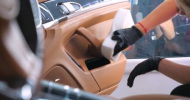 Araba yıkamacıdaki bir kadın özel kimya, giysi, sünger ve fırça kullanarak arabanın tüm parçalarını kuru temizlemeye verir. Tam araba temizliği, kuru temizleme, profesyonel hizmet. Araba, iş.