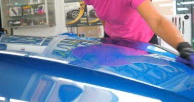 Araba yıkamacıdaki bir kadın özel kimya, giysi, sünger ve fırça kullanarak arabanın tüm parçalarını kuru temizlemeye verir. Tam araba temizliği, kuru temizleme, profesyonel hizmet. Araba, iş.