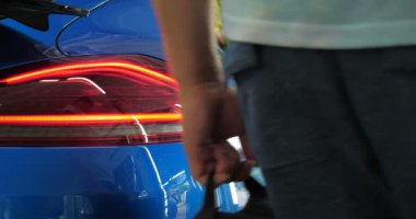 Garajda (Servis) bir adam çantasını salona koyar (bagajda), araba alarmını kontrol eder ve kapatır. Bir adam yeni bir arabanın bagajını ve kapısını açıyor. Yavaş çekim, araba dükkanı, adam.